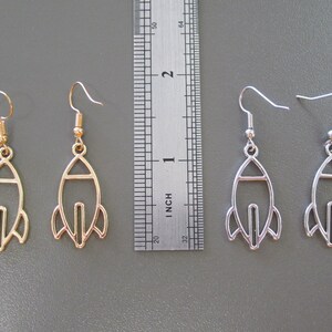Pu&ograve; includere: Due paia di orecchini a forma di razzo. Un paio &egrave; color oro, l'altro &egrave; color argento. Gli orecchini sono lunghi circa 3,8 cm, con chiusura a gancio. Il design del razzo presenta un contorno dettagliato dell'astronave.