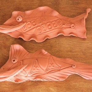 Peut inclure: Deux sculptures de poissons en terre cuite terracotta avec des sculptures détaillées. Les poissons sont de couleur terracotta naturelle non peinte.