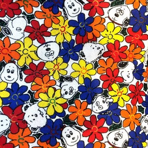 May include: A white background with a repeating pattern of black and white cartoon dogs and colorful flowers. The flowers are yellow, orange, red, and blue.