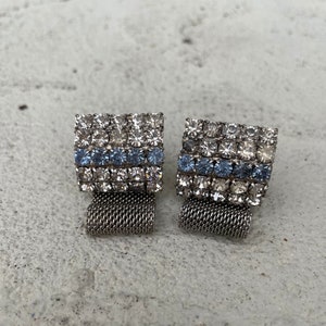 May include: A set of three ceramic mugs with a speckled, matte finish. The mugs are in shades of cream, light brown, and dark brown. Each mug has a simple, minimalist design and a rounded handle.