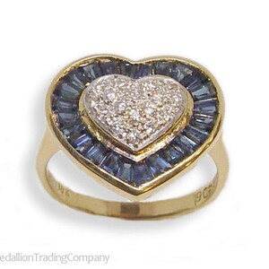 May include: A gold heart-shaped ring with a center diamond surrounded by a halo of blue sapphires. The ring is marked "14K" and "9CF".