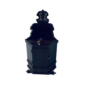 May include: A dark wood cabinet with a decorative top and a small bell inside. The cabinet has a hexagonal shape and is closed.
