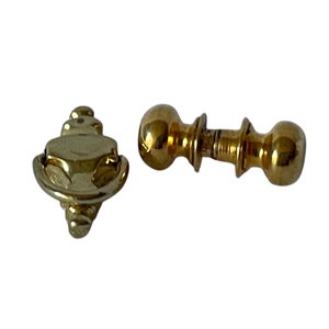 May include: Two gold door knobs, one is a traditional round knob and the other is a decorative ring pull.