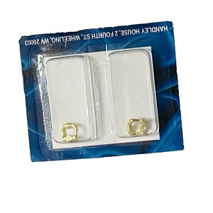 May include: Two gold-colored door handles packaged on a blue and silver card with the text "HANDLE HOUSE 2' FOURTH ST WHEELING WV 26003".