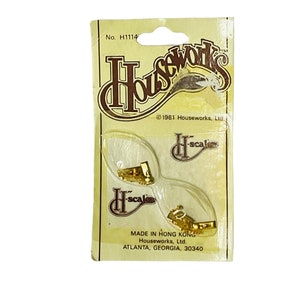 May include: A package of two gold-colored metal H-scale hooks. The package is labeled "Houseworks" and "Made in Hong Kong".