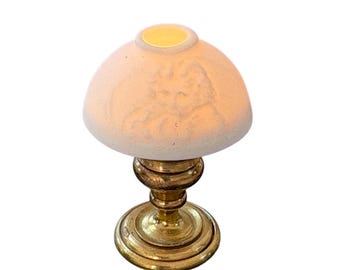 May include: A miniature table lamp with a cream-colored, dome-shaped shade featuring a detailed embossed design. The lamp sits on a gold-colored, ornate base. The lamp is a decorative accent piece.