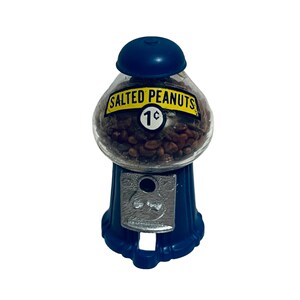 May include: A vintage-style peanut dispenser with a blue base and top. The clear glass globe is filled with salted peanuts and features a label that reads "SALTED PEANUTS 1&cent;". The dispenser has a coin slot.