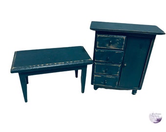 May include: A dark teal wooden table and a matching cabinet with four drawers and a door. Both pieces are distressed and have a rustic look.