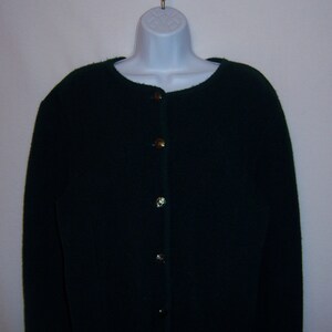 May include: A dark green cardigan with gold buttons. The cardigan has a round neckline and long sleeves.