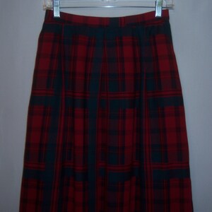 May include: A red and dark green plaid skirt with a pleated front.