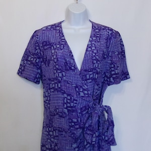 Puede incluir: Un vestido de envoltura de estampado morado y azul con mangas cortas y un lazo en la cintura.