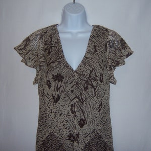 May include: A brown and beige sleeveless dress with a floral print and a V-neckline.