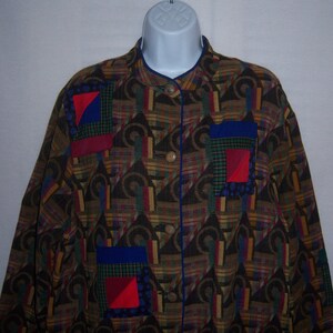 May include: A brown, blue, red, and green patterned shirt with a mandarin collar and a button-up front. The shirt has three patchwork pockets on the front, each with a different geometric pattern.