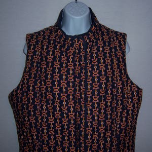 May include: A black quilted vest with a zipper closure. The vest has a repeating pattern of orange and pink chain links.