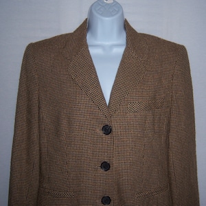 May include: A brown and black houndstooth blazer with three black buttons.