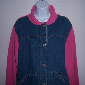 May include: A denim jacket with a pink knit collar and sleeves. The jacket has a button-up front and two front pockets. The sleeves and collar are a bright pink color, contrasting with the blue denim.