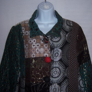 May include: A green, brown, and black patchwork jacket with a collar and button closure. The jacket has a variety of patterns, including circles, swirls, and geometric shapes.