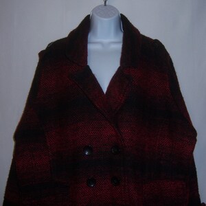 May include: A red and black plaid double-breasted coat with a collar and pockets.
