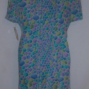 May include: A short-sleeved dress with a geometric pattern in shades of blue, green, and purple. The dress is displayed on a white hanger. The pattern is made up of small, irregular hexagons. The dress has a tag attached.