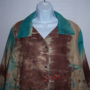 May include: A brown and beige tie-dye button-up shirt with a teal collar and embroidered floral details.