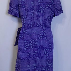 Puede incluir: Un vestido de envoltura de estampado morado y azul con mangas cortas y un lazo en la cintura.