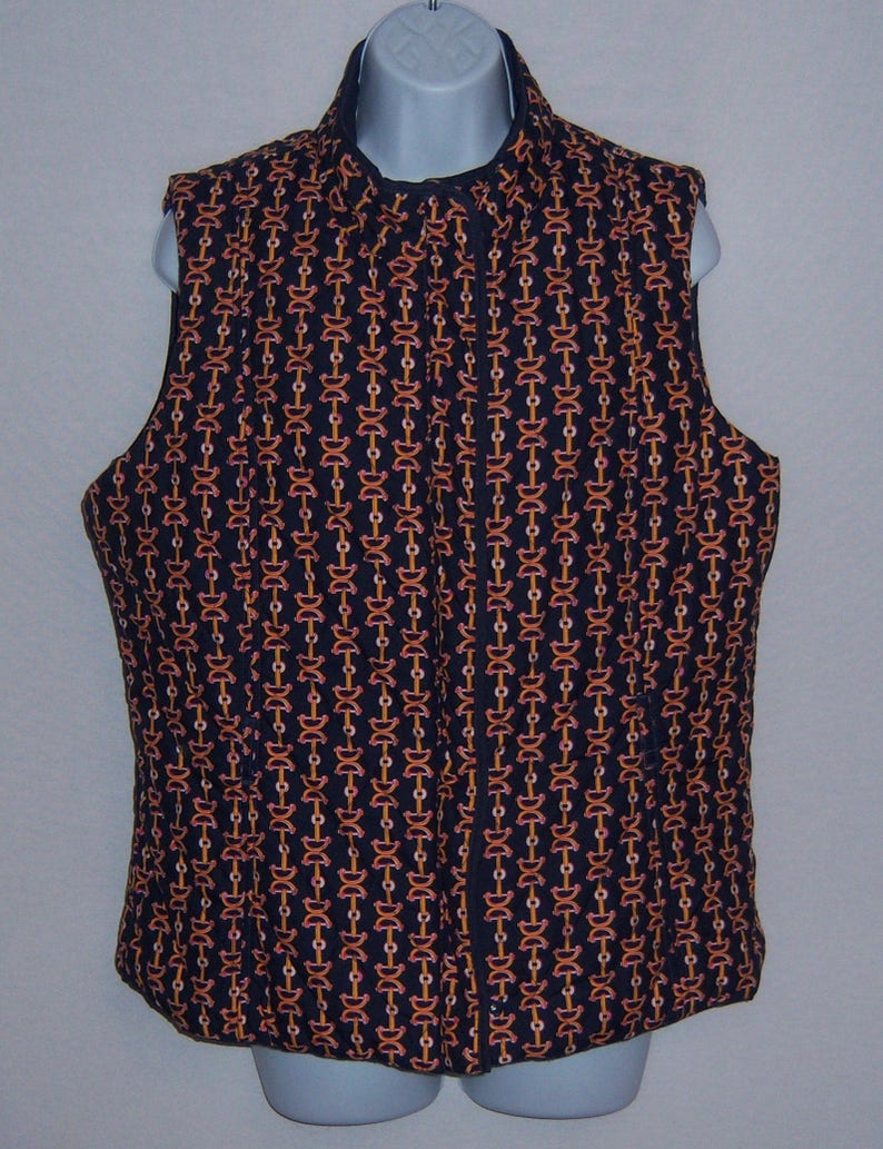 May include: A black quilted vest with a zipper closure and a geometric pattern of orange and white chains.