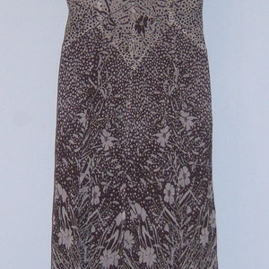 May include: A brown and white floral print dress with a scoop neck and short sleeves. The dress has a flowing, asymmetrical hemline.