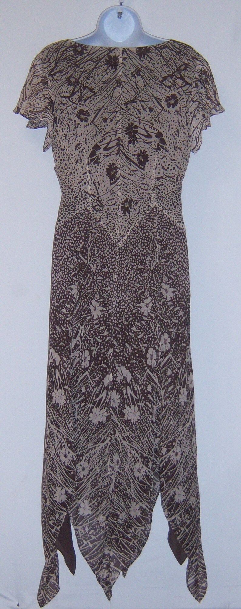 May include: A brown and white floral print dress with a scoop neck and short sleeves. The dress has a flowing, asymmetrical hemline.