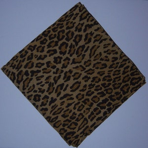 May include: A brown and black leopard print fabric with a square shape.