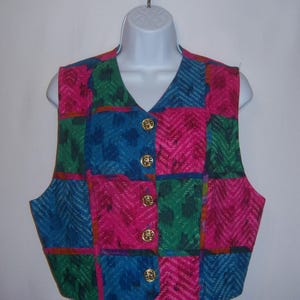 May include: A sleeveless vest with a patchwork design in shades of pink, blue, green, and orange. The vest has a V-neck and gold buttons.