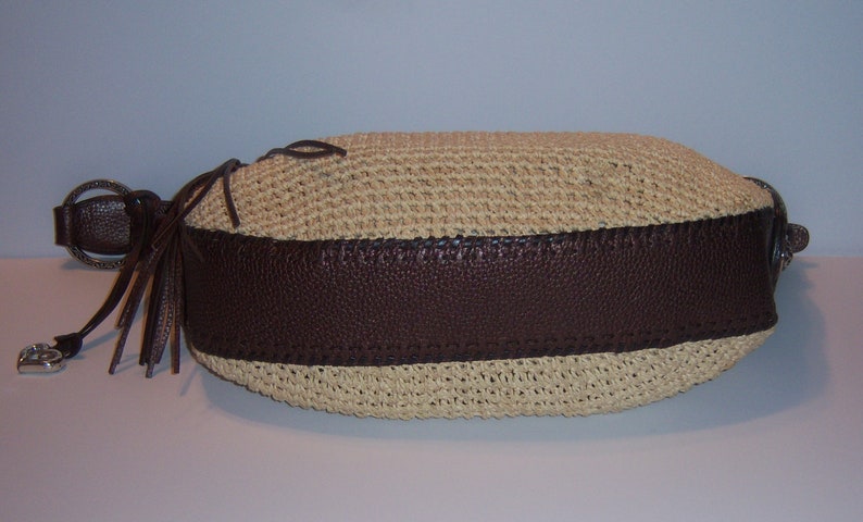 Może przedstawiać: Brązowa i beżowa pleciona torebka ze słomy z brązową sk&oacute;rzaną lam&oacute;wką i długim brązowym frędzlem.