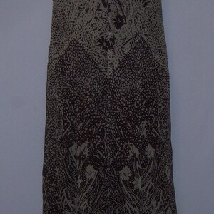 May include: A brown and beige sleeveless dress with a floral print and a V-neckline. The dress has a flowing, asymmetrical hemline.