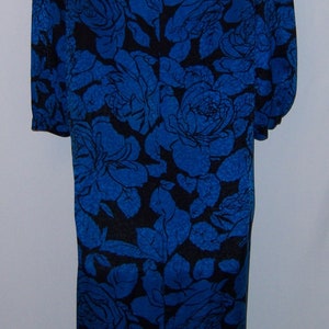 May include: A knee-length dress with a blue floral pattern on a black background. The dress has short sleeves and a keyhole opening at the back of the neck. The floral design features large roses and leaves.