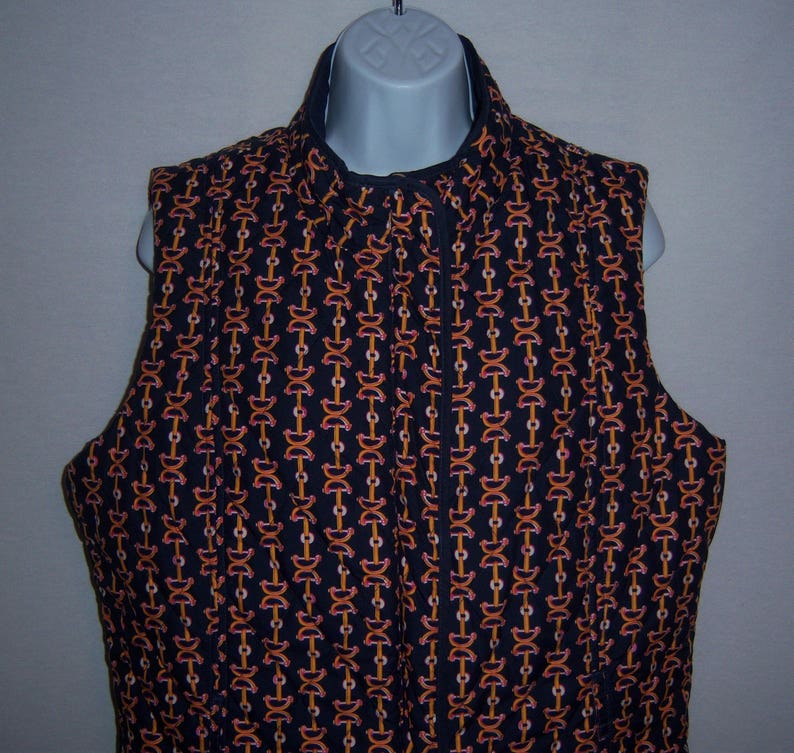 May include: A black quilted vest with a zipper closure. The vest has a repeating pattern of orange and pink chain links.