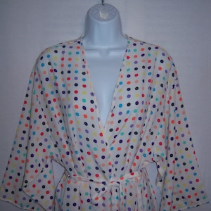 May include: A white robe with a colorful polka dot pattern. The robe has a V-neck and a tie belt.
