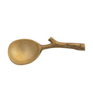 May include: A wooden spoon with a natural, branch-like handle. The spoon's bowl is a light, golden color, and the handle has a textured, brown finish. This unique kitchen utensil is designed for cooking and serving.