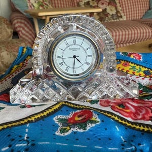 Peut inclure: Une horloge en cristal de Waterford avec une base en cristal clair et un cadran blanc avec des chiffres romains noirs. Le cadran de l'horloge indique "Waterford Crystal".