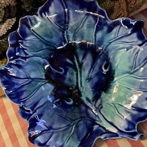 May include: A ceramic leaf-shaped dish with a glossy finish. The dish features a gradient of blue and teal hues, with darker shades in the center and lighter tones towards the edges. The dish is likely used for serving or display.