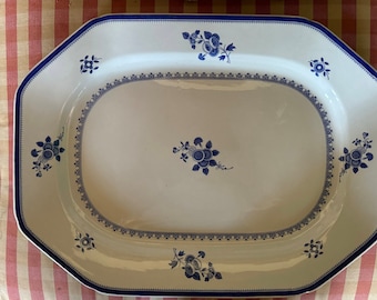 May include: A white octagonal serving platter with a blue floral design. The platter has a raised rim and a scalloped edge.