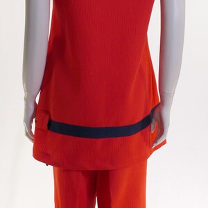 May include: A red ribbed knit jumpsuit with black trim on the sleeves and waist. The jumpsuit has a wide-leg style.