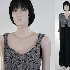 May include: A black and silver formal dress with a matching silver jacket. The dress has a sleeveless bodice with a sweetheart neckline and a flowing skirt. The jacket has a cropped length and a shawl collar.