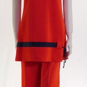 May include: A red two-piece outfit with a black trim. The top has a scoop neck and short sleeves. The pants have a wide leg.