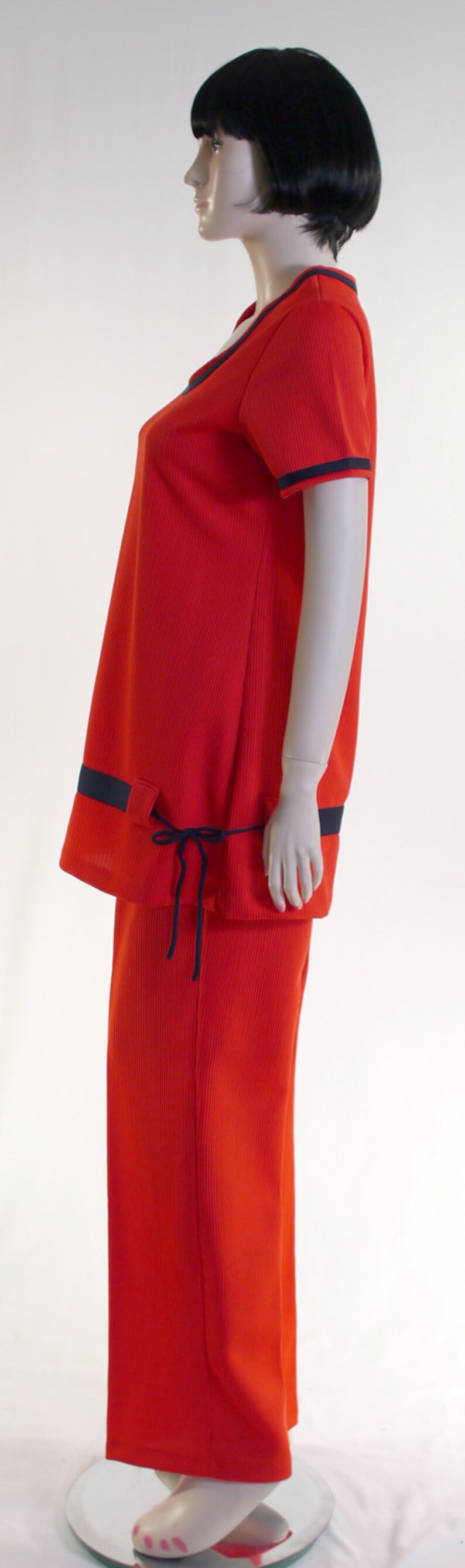 May include: A red ribbed knit jumpsuit with a navy blue trim and a tie at the waist.