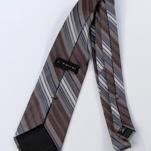 Puede incluir: Corbata a rayas marrones, grises y blancas con la etiqueta "J. Ferrar". La corbata es de tejido liso y est&aacute; en &aacute;ngulo sobre un fondo blanco. Las rayas son diagonales.