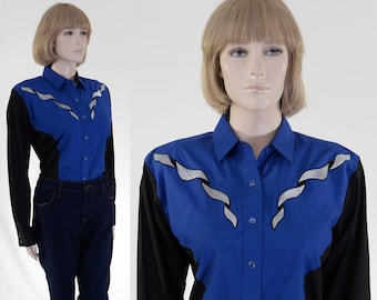 May include: A blue and black long-sleeved shirt with a silver embroidered design. The shirt has a button-up front and a pointed collar.