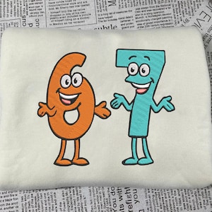 Könnte beinhalten: Gestickter Aufnäher mit den Zahlen sechs und sieben als Zeichentrickfiguren. Die Zahl sechs ist orange, die Zahl sieben ist türkis. Beide haben lächelnde Gesichter, Arme und Beine.