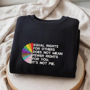 Op de afbeelding: Zwart sweatshirt met de geborduurde tekst "EQUAL RIGHTS FOR OTHERS DOES NOT MEAN FEWER RIGHTS FOR YOU. IT'S NOT PIE." Een kleurrijk taartdiagram staat links.