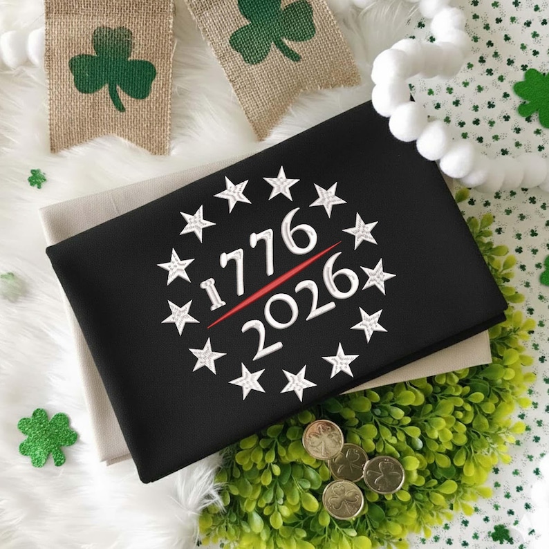 May include: Black fabric with the text "1776 2026" in white, surrounded by stars. A red line underlines the numbers. The image includes shamrock decorations and a banner with a green shamrock.