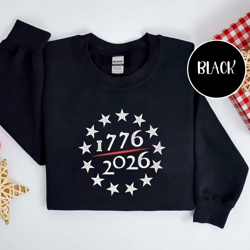 May include: Black sweatshirt with a white star design around the numbers "1776" and "2026" in a circle. The word "BLACK" is in a white circle in the upper right corner.