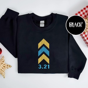 May include: Black crewneck sweatshirt with a design of three upward-pointing chevrons in yellow and blue, with the number 3.21 below. The word "BLACK" is in a white circle in the upper right corner.